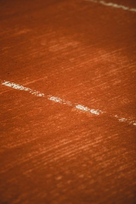 Close-up image of a wooden floor in an indoor setting, showing a light, narrow scratch running diagonally across the reddish-brown surface. The background reveals a blurred view of the wooden flooring with a subtle sheen. The image appears to be taken with a mobile device, evident by the slight focus differences and lighting reflections. This detailed shot highlights the potential damage or wear on flooring, which may be relevant during home relocation or furniture transport assessments. The setting is typical of a residential interior, and the floor's condition could influence packing and moving decisions managed by companies like Man With a Van Earls Court, especially when handling furniture or appliances that require careful loading and transport. The photo emphasizes the importance of inspecting flooring integrity during the planning phases of removals or house moves in the Earls Court area.