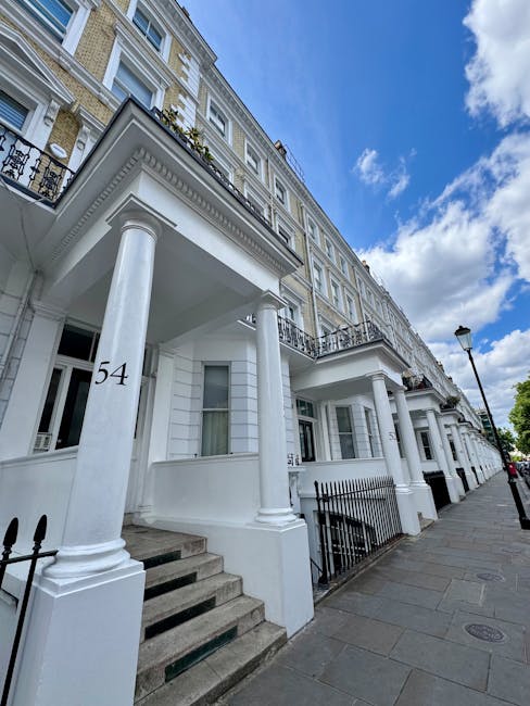 Photograph of a multi-storey residential building on Earls Court Road, showing the exterior brick facade with multiple white-framed windows and sloped roofs. On the street in front, several parked car